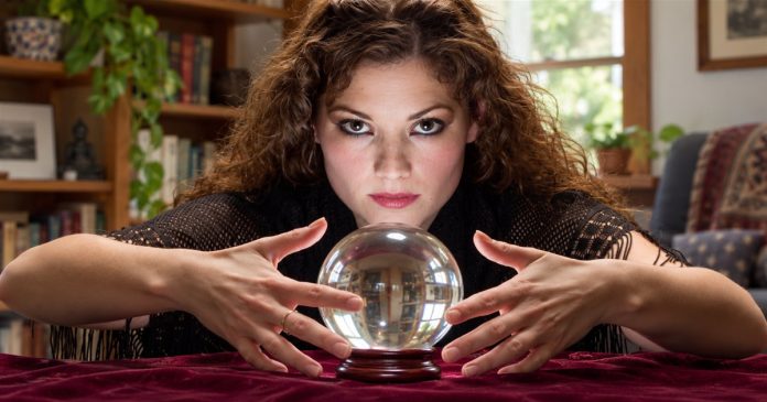 Conflicting predictions — repaired existing cover Woman seated at a home table with her hands beside a clear glass crystal ball