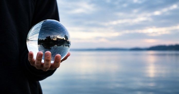 Crystal ball archive cover — horizontal repair A hand holding a clear glass ball beside a softly blurred waterside landscape.
